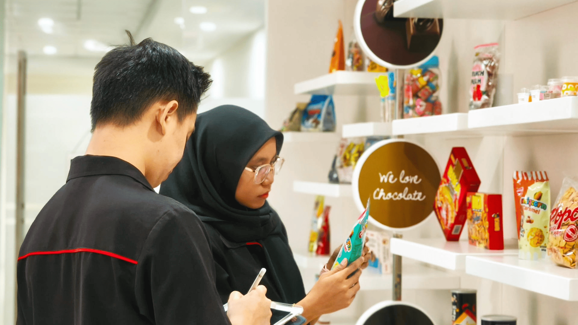 Pelanggan memeriksa produk cokelat dan permen di rak display